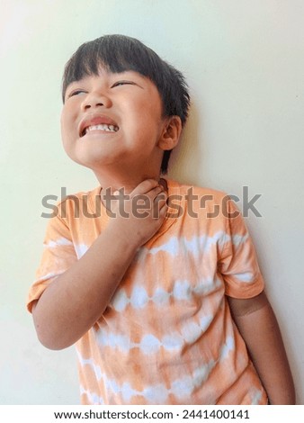 Ill little boy with sore throat on gray background