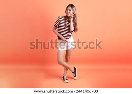 The young Asian woman in casual clothes with gesture of two finger or V Sign  on the orange background 