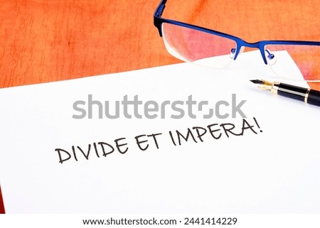 Latin quote Divide et impera meaning Divide and conquer. the best method of governing such a state is to incite and use hostility between its parts. Text written on a white piece of paper