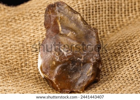 Stone scraper made of red-yellow chalcedony, Stone Age tool Royalty-Free Stock Photo #2441443407
