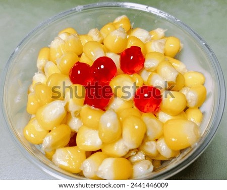 a photography of a bowl of corn with jellys and cherries.