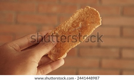 photo of hand holding a typical Indonesian food, namely rambak crackers