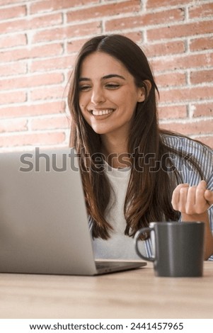 One happy young lady using laptop to videocall friends or business team smiling at the display and gesturing. People and smart working home office workplace lifestyle. Communication with computer Royalty-Free Stock Photo #2441457965
