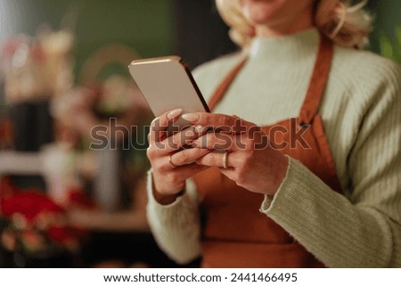 A lifestyle image of a florist using a smartphone amidst a soft-focus floral backdrop