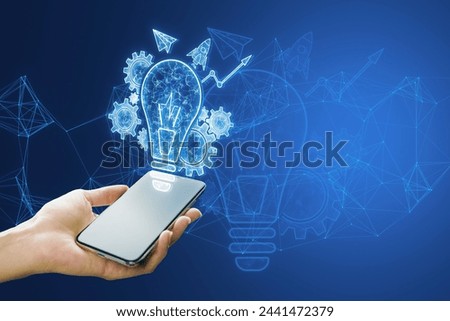 Close up of female hand holding smartphone with glowing blue lightbulb, cogwheel and arrow hologram on polygonal background. Innovation and creative idea concept