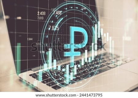 Close up of laptop with creative round ruble hologram on blurry grid background with forex chart. Online banking, cryptocurrency and finance concept. Double exposure
