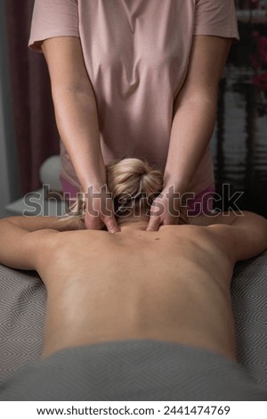 A woman undergoing a massage of the cervical-collar area. Vertical photo.