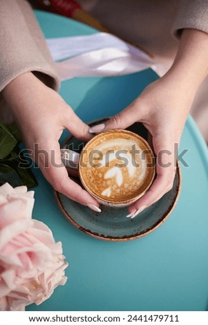 A cup of coffee in the hands of a girl on the cafe table. Aesthetically beautiful. The concept of a holiday, a date, a love story