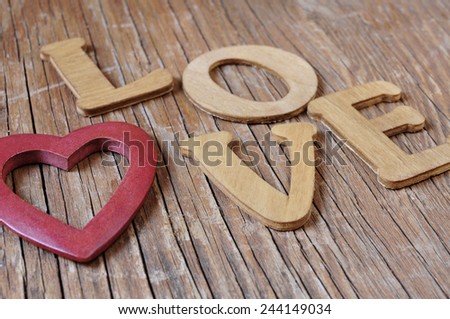 a wooden heart and wooden letters forming the word love on a rustic wooden surface
