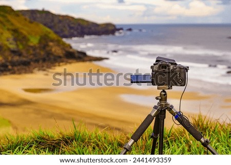 Professional camera on tripod taking picture film video of sea coastal landscape, Carniciega beach on Asturias coast. Autumn seaside view in northern Spain.