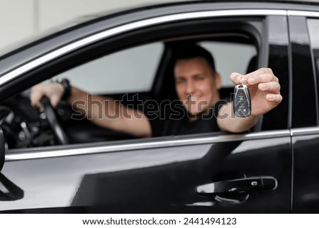 Happy man driver sits in the car and holds the keys. Buying and renting a car. Sale
