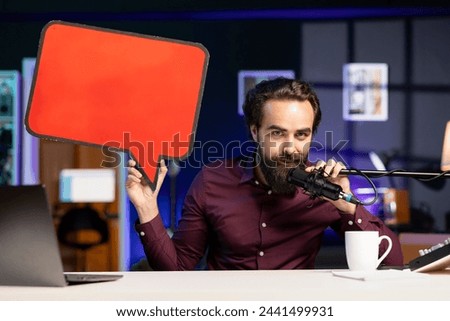 Influencer filming content, holding empty copy space sign, talking in professional microphone. Online star using cardboard bubble speech cutout to do influencer marketing, speaking in high tech mic Royalty-Free Stock Photo #2441499931