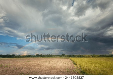 A rainbow in the cloudy sky over the fields, Nowiny, eastern Poland