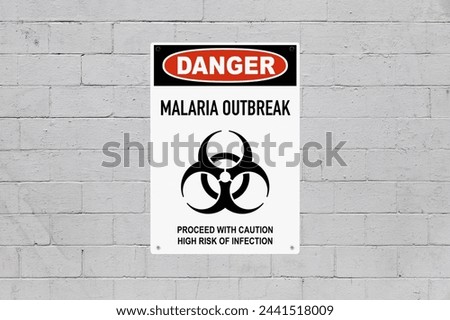 Black, red and white danger sign attached on a brick wall painted in grey. The sign stating “Danger - Malaria outbreak - Proceed with caution, high risk of infection”.