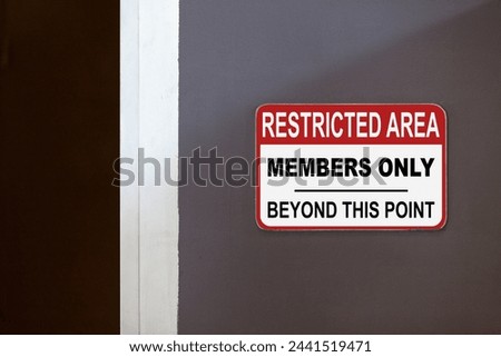 Red and white restricted area sign on the side of an open door stating : Restricted Area, members only beyond this point. Royalty-Free Stock Photo #2441519471