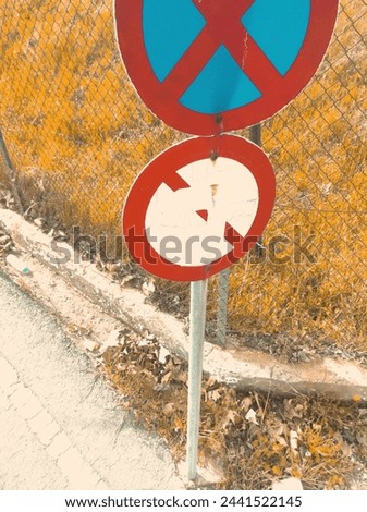 An aged traffic sign stands weathered by time, positioned alongside the road with tufts of grass peeking out behind it.