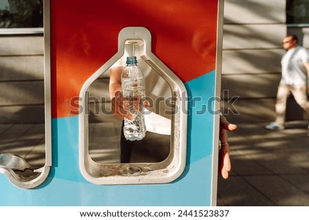 Woman refilling her water bottle at city. Free public water bottle refill station. Sustainable and green city. Tap water to reduce plastic bottle usage. Drinking water dispenser Royalty-Free Stock Photo #2441523837