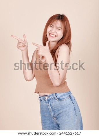 Portrait of young beautiful redhead girl woman cheerful smiling look sideways. attractive cheerful slender carefree girl isolate on bright yellow background. pointing finger to the side.