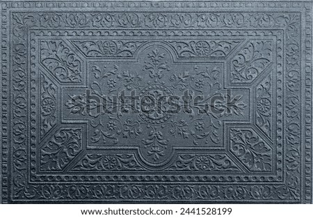 Detailed embossed pattern graces a dark surface, showcasing intricate designs reminiscent of classic ornamental artwork.