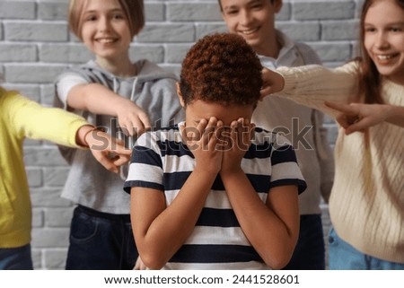 Bullied little African-American boy crying at school, closeup Royalty-Free Stock Photo #2441528601
