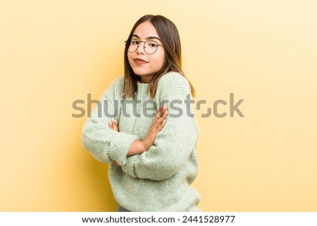 pretty hispanic woman shrugging, feeling confused and uncertain, doubting with arms crossed and puzzled look