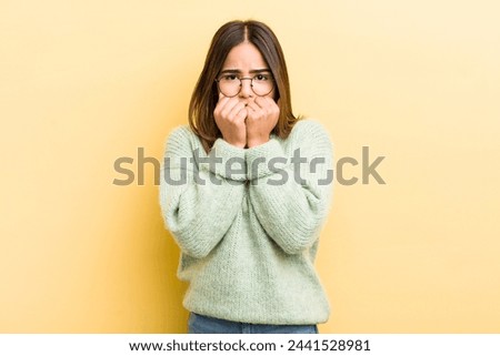 pretty hispanic woman looking worried, anxious, stressed and afraid, biting fingernails and looking to lateral copy space