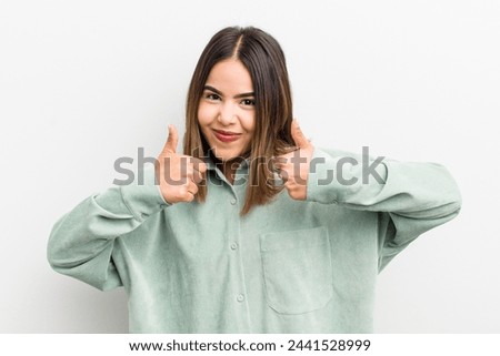 pretty hispanic woman smiling broadly looking happy, positive, confident and successful, with both thumbs up