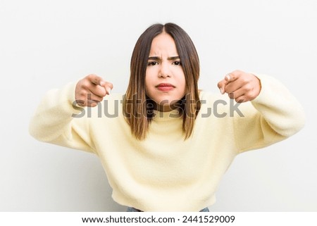pretty hispanic woman pointing forward at camera with both fingers and angry expression, telling you to do your duty