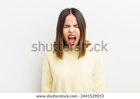 pretty hispanic woman shouting aggressively, looking very angry, frustrated, outraged or annoyed, screaming no