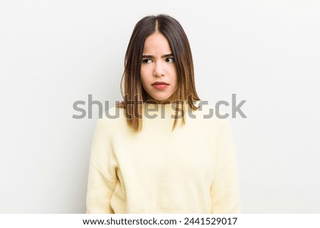 pretty hispanic woman feeling sad, upset or angry and looking to the side with a negative attitude, frowning in disagreement