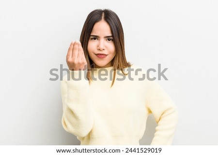 pretty hispanic woman making capice or money gesture, telling you to pay your debts!