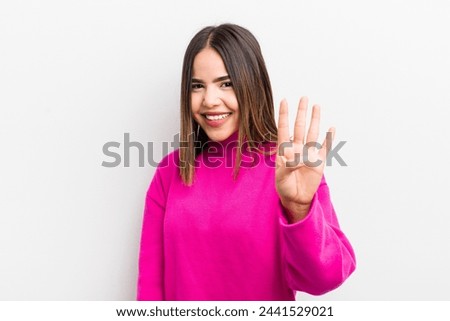 pretty hispanic woman smiling and looking friendly, showing number four or fourth with hand forward, counting down