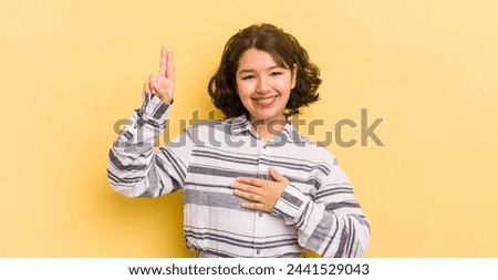 pretty hispanic woman looking happy, confident and trustworthy, smiling and showing victory sign, with a positive attitude