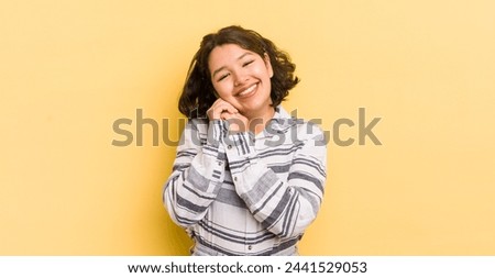 pretty hispanic woman feeling in love and looking cute, adorable and happy, smiling romantically with hands next to face