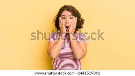 pretty hispanic woman feeling shocked and scared, looking terrified with open mouth and hands on cheeks