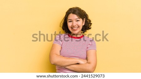 pretty hispanic woman looking like a happy, proud and satisfied achiever smiling with arms crossed