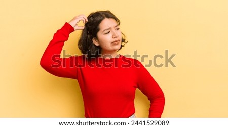 pretty hispanic woman feeling puzzled and confused, scratching head and looking to the side