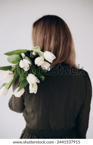a girl in a green dress with white tulips