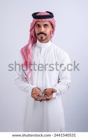 Saudi man holding coins in hand isolated on white background
