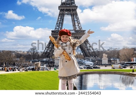 Paris travel concept with a cute blonde girl holding a french baguette bread in front of the Eiffel Tower