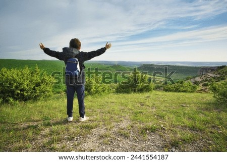 Boy standing and looking at mountainous landscape. People and nature scene.