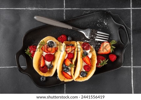 Pancake tacos. Portion of sweet dessert taco made with pancake, whipped cream, cottage cheese or ice cream, fruit and berries. Summer breakfast or brunch recipe, copy space