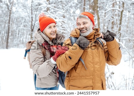 Mature couple in a winter forest feeling happy