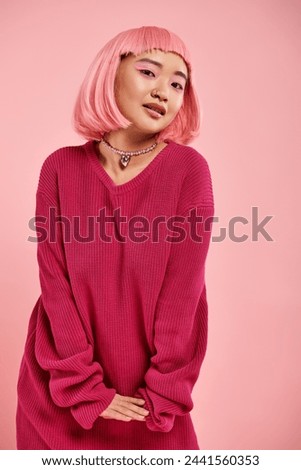 playful asian woman with pearl necklace in vibrant sweater outfit cute posing on pink background