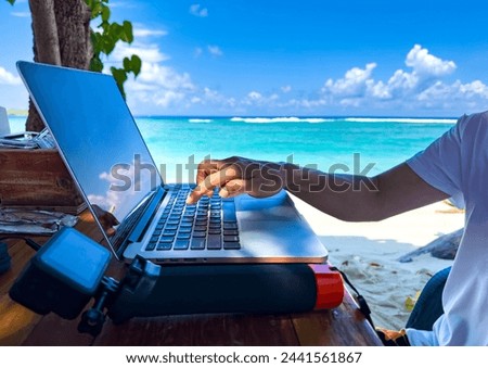 Nomad digital with laptop and running remotely with bright scenic view near poolside on the beach in summer time