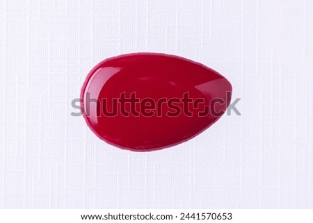 Splattered red nail polish or paint on white background. Splash of dark red nail polish. Top view