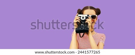 Portrait of happy young woman photographer with film camera, female on violet studio background, copy space for advertising text