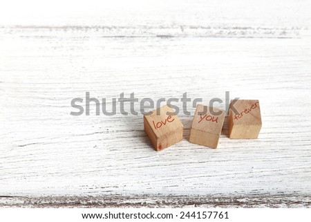 Three wooden cubes with " LOVE YOU FOREVER " words on white wood, background for valentine's day.
