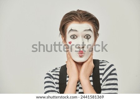 A pantomime theater actor plays the role of a young man in love, blowing a kiss. White studio background with copy space. Mime in love.
