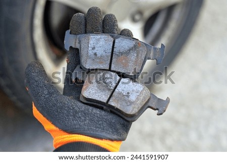 Mechanic holds defective pads in his hand, replacing worn uneven defective pads. Vehicle brake system service, brake pad replacement. Car maintenance. Selective focus Royalty-Free Stock Photo #2441591907